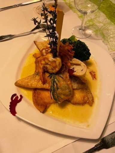 Frittierter Fisch mit Gemüse und Sauce in elegantem Anrichten.