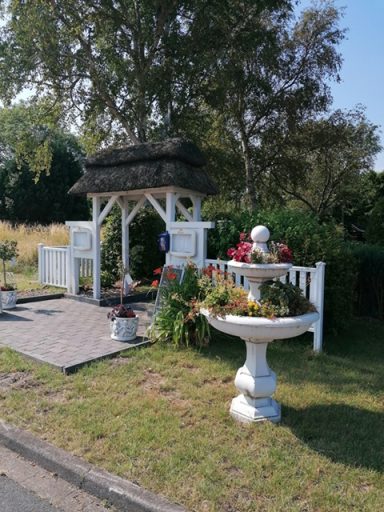 Blumenbeet mit Pavillon, bunten Pflanzen und dekorativen Elementen in einem Garten.