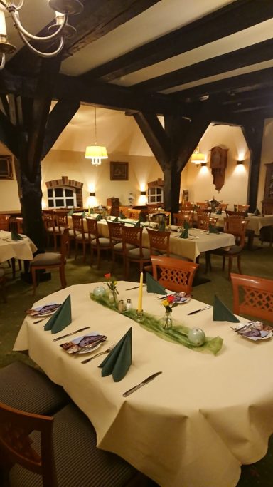 Gemütliches Restaurant mit gedeckten Tischen, Holzdecke und warmem Licht.