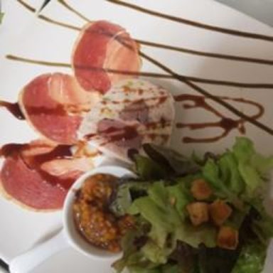 Ein Teller mit dünn geschnittenem Fleisch, Salat und einer Sauce.