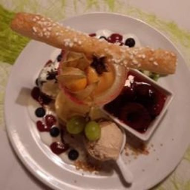 Ein Dessertteller mit Eis, Früchten, einer Waffel und Soße.