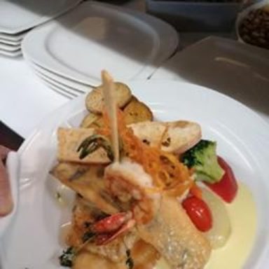 Ein Teller mit gebratenem Fisch, Gemüse und Kartoffeln in einer cremigen Sauce.