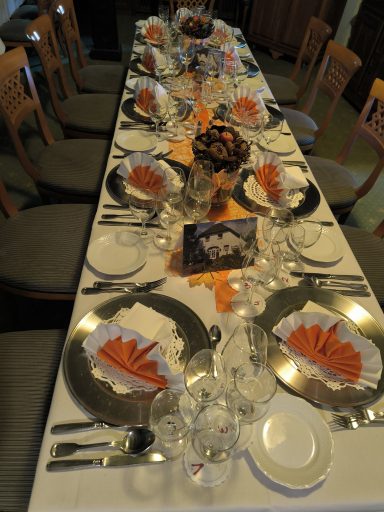 Elegant gedeckter Tisch mit orangefarbenen Servietten und festlicher Dekoration.