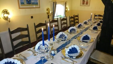 Elegant Tischdekoration mit blauen Akzenten, Kerzen und feinem Geschirr.